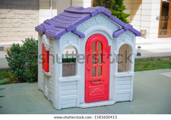 plastic colorful house . Entertainment area.kids\
playhouse in the entertainment center. Plastic children play house\
. Green floor. Joy and fun. Playing games.with red door and red\
window .Game house .