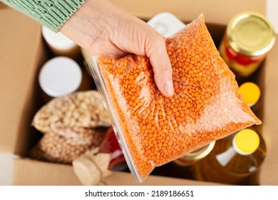 Plastic Container With Lentils In Female Hand On Emergency Food Box Background