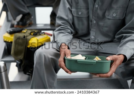 Plastic container with lunch in hands of builder having break