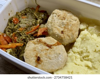 Plastic Container With Mashed Potatoes, Two PanFried Cutlets And SautEd Carrots And Greens On Wooden Desk, Midday Office Setting With Natural Light, BudgetFriendly Homemade Reheatable