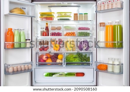 plastic containers with different fruits and vegetables in a open fridge. frozen food storage.