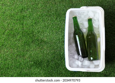 Plastic Cool Box With Bottles Of Beer And Ice Cubes On Green Grass Outdoors, Top View. Space For Text