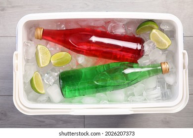 Plastic Cool Box Filled Ice Cubes, Lime And Refreshing Drinks On Wooden Floor, Top View