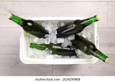 Plastic Cool Box With Ice Cubes And Beer On Wooden Floor, Top View