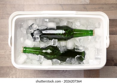 Plastic Cool Box With Ice Cubes And Beer On Wooden Floor, Top View