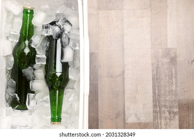 Plastic Cool Box With Ice Cubes And Beer On Wooden Floor, Top View. Space For Text