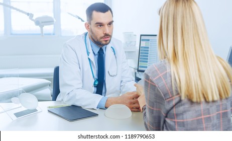 Plastic / Cosmetic Surgeon Shows Female Patient Breast Implant Samples For Her Future Surgery. Professional And Famous Surgeon Working In Respectable Clinic.