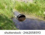 Plastic culvert pipe as a water passage under a dike at a ditch as a connection. Ribbed outside, smooth inside. Spring, May, Netherlands