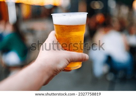 plastic cup glass with beer in hand. Outdoor summer festival