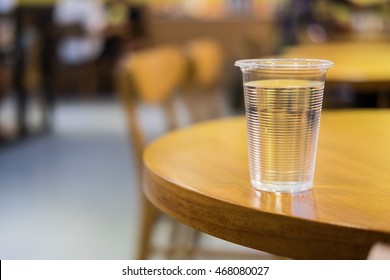 Plastic Cup Of Water On Round Wooden Table