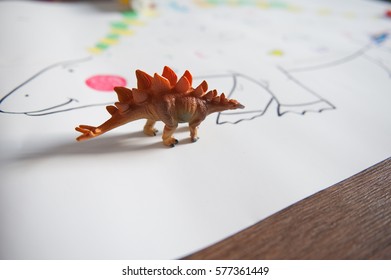 Plastic Dinosaur Toy.  Little Boy Draws Reptile On The Drawing Paper On The Floor.