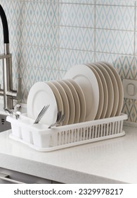 A plastic dish drying rack stands at the sink in the kitchen with clean dishes inside.