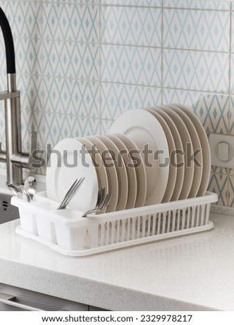 A plastic dish drying rack stands at the sink in the kitchen with clean dishes inside.