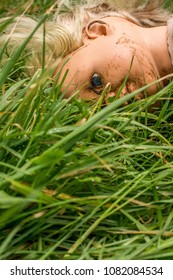 Plastic doll facing down in long grass.