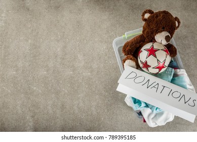 Plastic Donation Box With Toys, Clothes And Food, White Grey Background Copy Space Top View