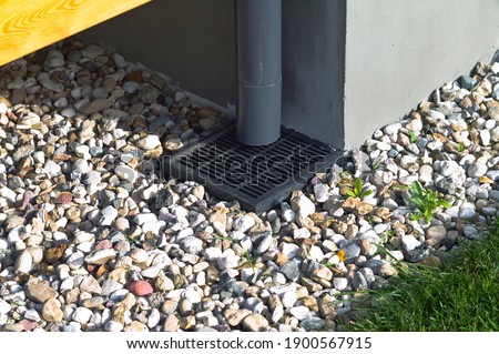 Plastic downspout, grill and pebble around a house, outdoor close up