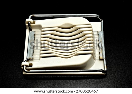 A plastic egg slicer kitchen tool. Designed for quickly and evenly slicing hard-boiled eggs.