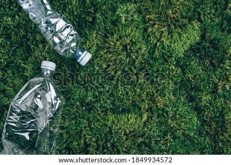 Plastic empty rumpled bottles on green moss background. Top view, copy space. Zero waste. Pollution, environmental protection concept. Reuse garbage, recycle, plastic free. Earth, world water day.