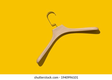 Plastic fashionable hanger under a tree on a yellow background with a hard shadow. Concept store, sale, design, empty hanger. Fashionable lightweight hangers made of durable material