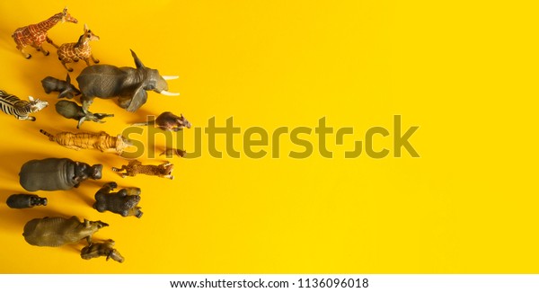 Plastic figurines of\
animals in hot countries. Protection of the animal. Children\'s toy.\
Yellow background.