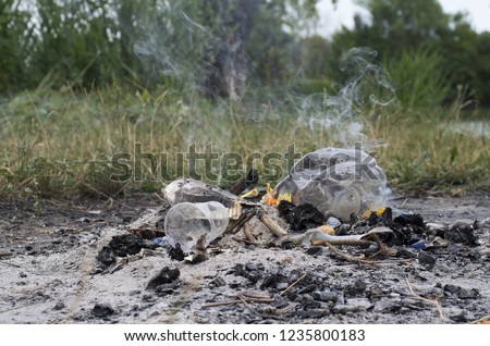 Plastic fire. Environmental pollution: after picnic a fire with a flame burns plastic (plastic containers, bottles and glasses) producing dioxin and toxic air (the smoke of this photo is real)