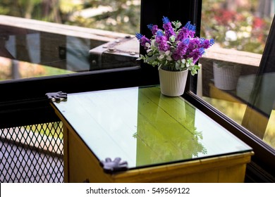 Plastic Flower Pot On A Glass Table.