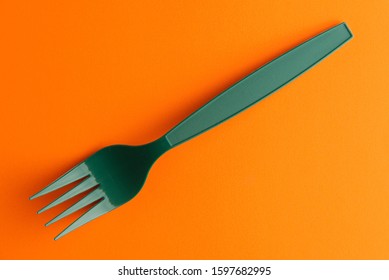 Plastic Fork Isolated On Orange Background, Green Plastic Fork