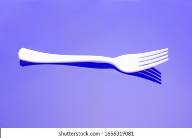 Plastic Fork On Colored Background; Fork For Casual Food, Covered In White To Prick And Make Casual Food, Ideal For Family Meals, Parties, Catering.