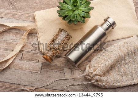 Plastic free recycled textile produce bag for carrying fruit or vegetables on a wooden surface. Reusable cotton, textile bags, a steel water bottle and glass jars  for zero waste grocery shopping.