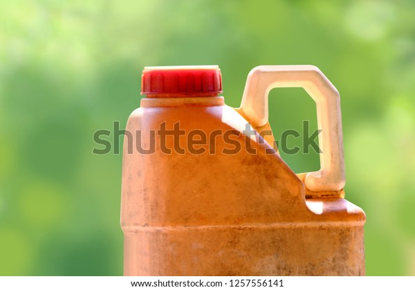 plastic gallon yellow old of oil lubricant\
isolated on blurred green background, close up old and dirty car\
engine oil gallon, plastic container, oil gallon for automotive\
maintenance service