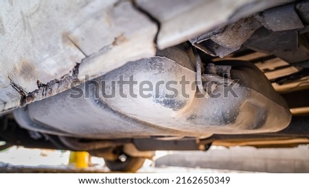 Plastic gas tank installed in a car with a rusty rotting body, bottom view