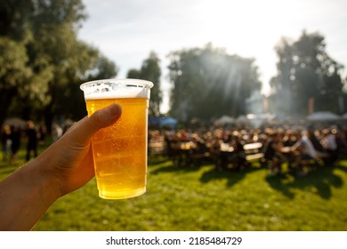 A plastic glass of beer in hand. Outdoor summer festival