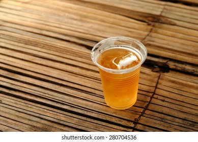 A Plastic Glass Of Beer On Bamboo Table