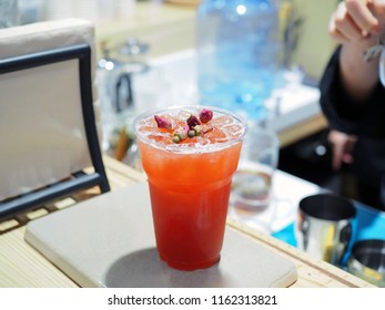 A plastic glass of Iced rose tea decorated with cinnamon stick and dried rose on the table. Summer cocktail or tropical mocktail, Healthy drink concept.