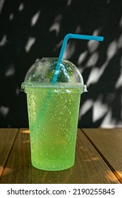 A Plastic Glass With A Straw And A Drink Stands On A Table Outside. Soft Selective Focus