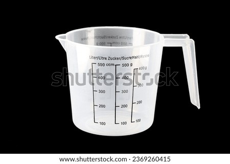 Plastic kitchen measuring cup on isolated black background. Close up