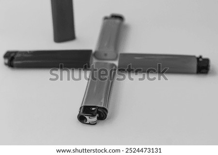 Plastic lighters with mechanical ignition, a compact item, household items for people with a bad habit. Black and white horizontal photo from top to bottom.