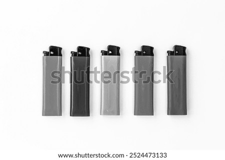 Plastic lighters with mechanical ignition, a compact object, located in one line. Black and white horizontal photo from top to bottom.