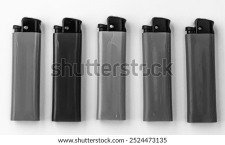 Plastic lighters with mechanical ignition, a compact object, located in one line. Black and white horizontal photo from top to bottom.