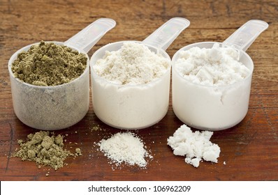 Plastic Measuring Scoops Of Three Protein Powders (from Left Hemp Seed, Whey Concentrate, Whey Isolate) On A Grunge Wood Surface