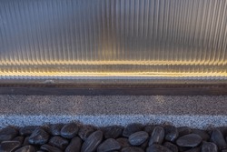 The Plastic Mirror Is Lit By LED Strip Lights Inside. Below Is A Granite Ledge And River Rocks
