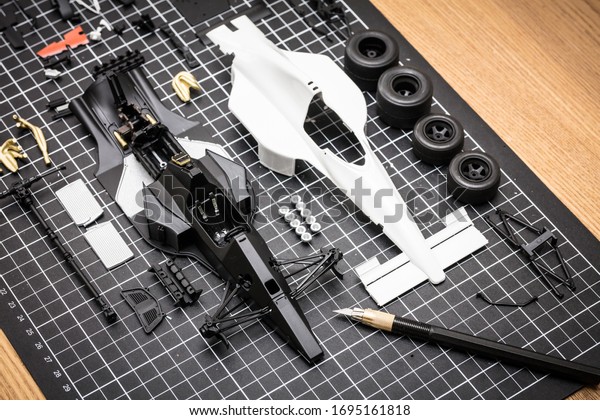 A plastic model toy car kit being built in a\
home envornment