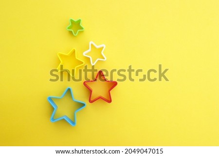 Plastic molds of multi colors for making cookies in the shape of a star on a yellow background.
