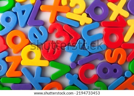 Plastic multi-colored alphabets letters on a magnet.
Lots of сolorful letters scattered on a white background. The concept of elementary school background texture for children. Top view closeup.