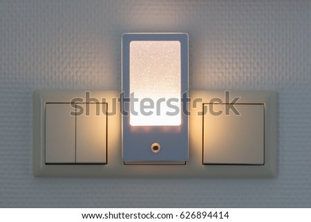 Plastic nightlight illuminating the wall and light switch