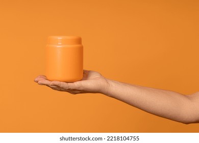 Plastic Opaque Jar Of Yellow Color On A Female Palm On A Yellow Background