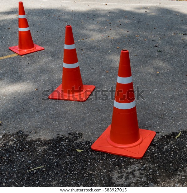 Plastic orange cone on\
the asphalt road
