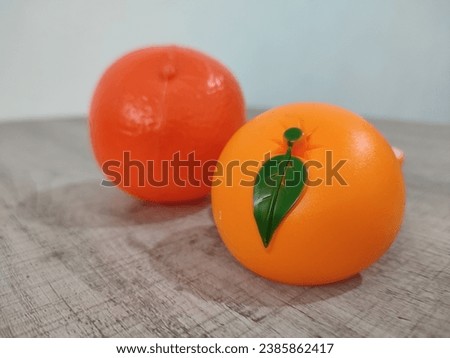 Plastic orange fruit toy for children to learn fruit names, fruit cutting toy. Isolated orange fruit artificial plastic toy, selective focus.
