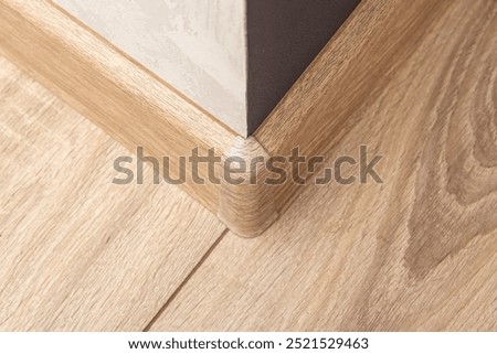 Plastic outer corner of floor skirting board. Plastic skirting boards with wood texture
