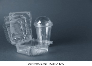 Plastic packaging. Disposable containers and cups on grey background, closeup with space for text